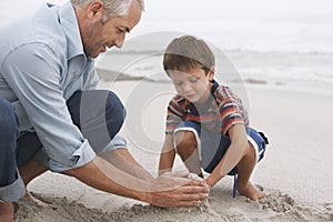 Father And Son Making Sand Castle On Beach