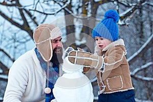 Father and son making snowman in the snow. Handmade funny snowman. Christmas holidays and winter new year with father