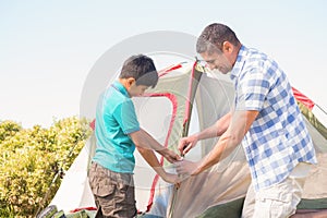 Father and son pitching their tent