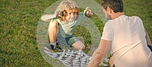 Father and son play chess outdoor, banner poster with copy space, happy family. parenthood and childhood. checkmate