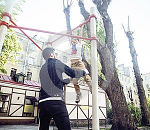 Father with son on playground training, happy family smiling outside, lifestyle people concept