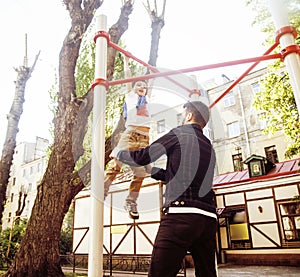 Father with son on playground training, happy real family smiling outside, lifestyle people concept