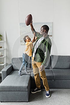 father and son playing with american football ball