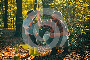 Father and son playing in the autumn forest. Little boy with his father talking in autumn outdoors. Stylish man with son