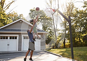 Father And Son Playing Basketball On Driveway At Home