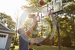 Father And Son Playing Basketball On Driveway At Home