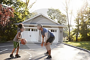 Father And Son Playing Basketball On Driveway At Home