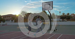 Father and son playing the basketball in hoop with sun-flare.