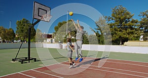 Father with son playing basketball on outdoor court.