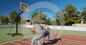 Father and son playing basketball on the street and throwing a ball to the basket.