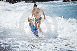 Father and son playing on the beach in rough water