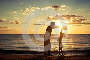 Father and son playing on the beach at the sunset time.