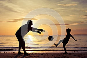 Father and son playing on the beach at the sunset time.