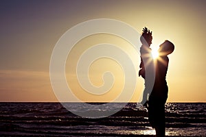 Father and son playing on the beach at the sunset time.