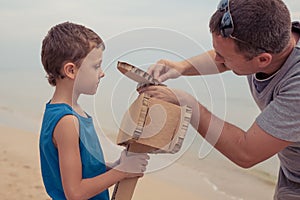 Father and son playing with cardboard toy airplane