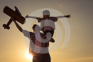 Father and son playing with cardboard toy airplane in the park a