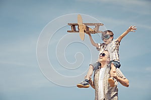 Father and son playing with cardboard toy airplane in the park a