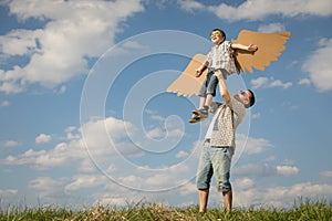 Father and son playing with cardboard toy wings