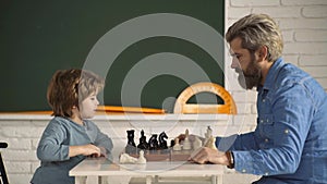 Father and son playing chess game. Little clever boy thinking about chess. Games and activities for children. Dad and