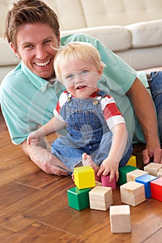 Father And Son Playing With Coloured Blocks At Hom