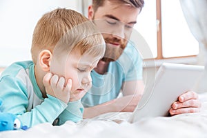 Father and son playing computer games on tablet at home