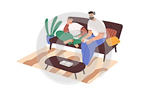 Father and son playing console video game, sitting on sofa at home. Family, dad and teenager boy with headphones and