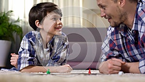 Father and son playing exciting board game, parent developing boys skills