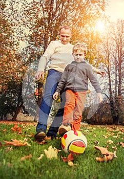 Father with son playing in football at the autumn park