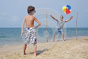 Father and son playing football on the beach