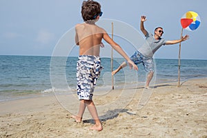 Father and son playing football on the beach