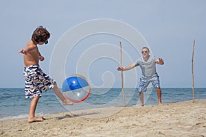 Father and son playing football on the beach