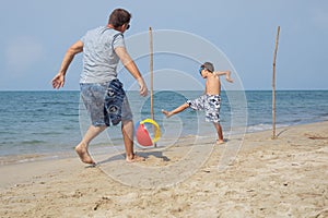Father and son playing football on the beach