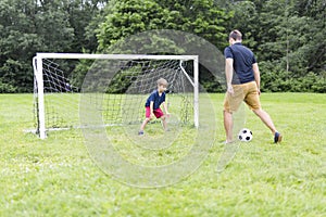 Father with son playing football on football pitch