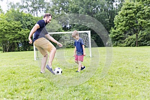 Father with son playing football on football pitch