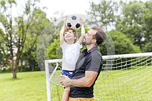 Father with son playing football on football pitch