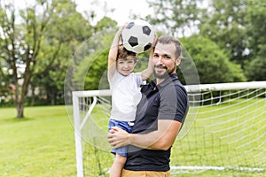 Father with son playing football on football pitch