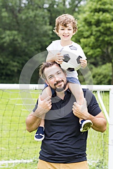 Father with son playing football on football pitch