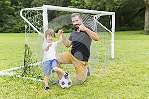 Father with son playing football on football pitch