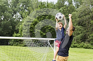 Father with son playing football on football pitch