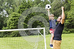 Father with son playing football on football pitch