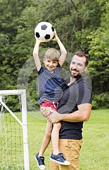 Father with son playing football on football pitch