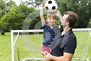 Father with son playing football on football pitch