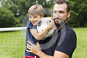 Father with son playing football on football pitch