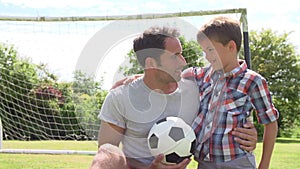 Father And Son Playing Football In Garden At Home