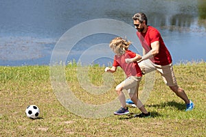 Father and son playing football together. Dad with kid spend hours practicing passing and kicking soccer ball. Dad and