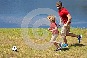 Father and son playing football together. Dad with kid spend hours practicing passing and kicking soccer ball. Dad and