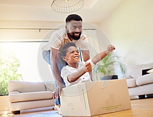 Father, son and playing at home with pretend car in a box on moving day in new property. Black family, house and real