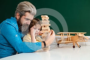Father and son playing jenga game at home. Elementary school and education. Cute pupil and his father schooling work.