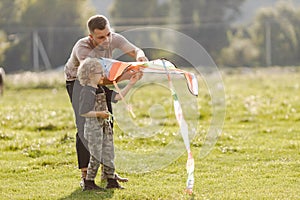 Father and son playing with a kite on summer outdoors