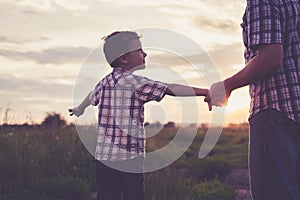 Father and son playing in the park at the sunset time.